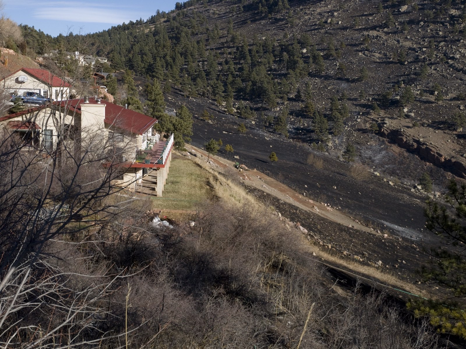 Homes surrounded by green defensible space beside a charred hillside after the 2009 Old Stage Fire near Boulder, Colorado — photo by Michael Rieger, FEMA, public domain
